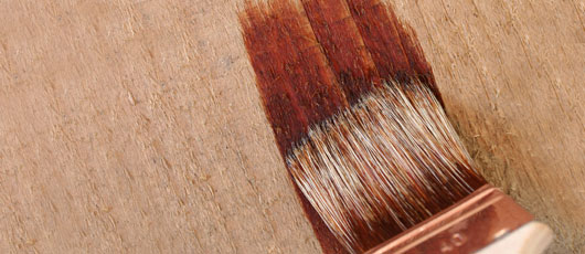 Pinsel beim aufbringen von Farbe auf grobes Holz
